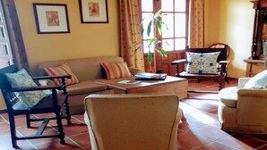 Una sala de estar con sofá, sillones, una mesa de centro y una planta en maceta.