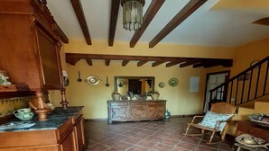 Amplia sala de estar con piso de baldosas, mobiliario de madera y una escalera.