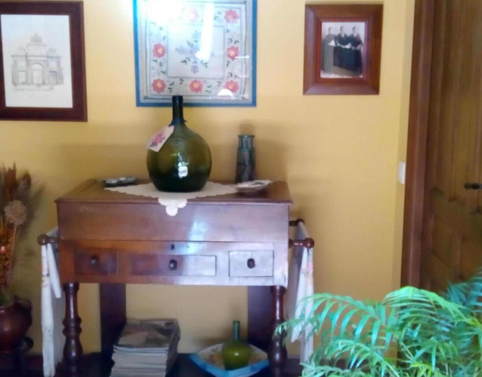 Een houten tafel met een vaas, foto's in lijsten en een plant.