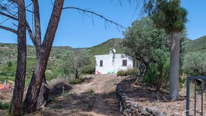 Ein rustikales Gebäude mit Steineingang, blauem Himmel und hügeliger Landschaft im Hintergrund.