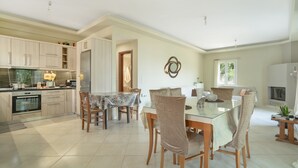 Una cocina amplia con electrodomésticos modernos, un comedor con mesa de vidrio y una sala de estar acogedora con chimenea.