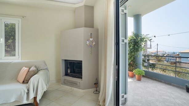 Una sala de estar con sofá, chimenea y balcón con plantas en macetas.