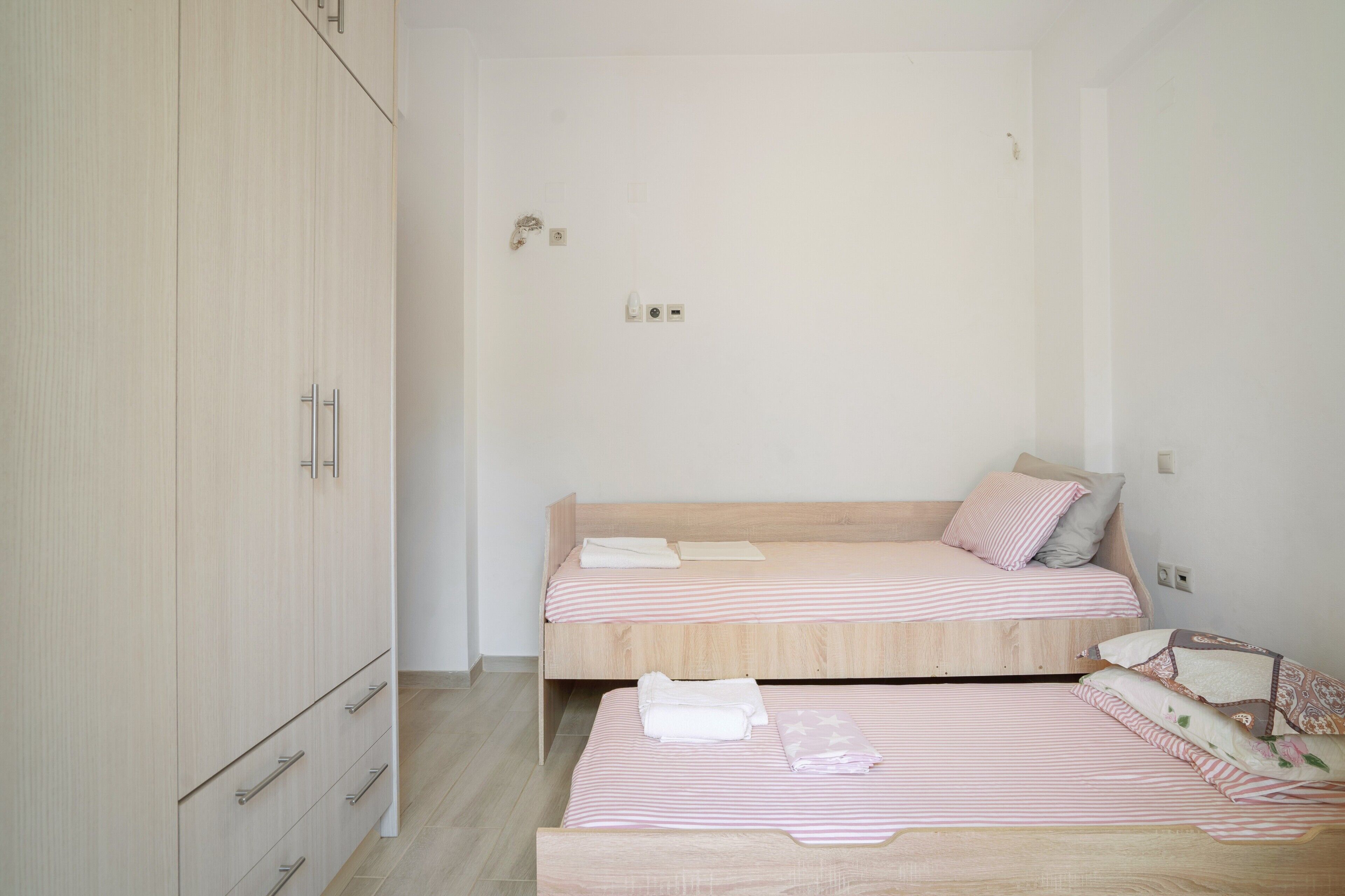 A bedroom with two beds, a wardrobe, and a door with a lock and light switch.