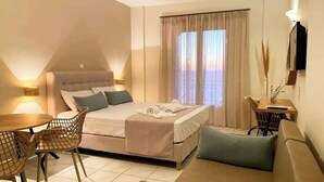 A bedroom with a bed, a sofa, a dining table, and chairs.