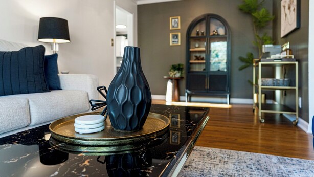 A modern living room with a sofa, a coffee table, a lamp, and a decorative vase.