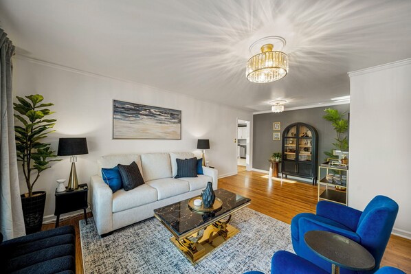 A modern living room with a white sofa, blue armchair, and a black coffee table.