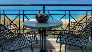 A balcony with a table and chairs, a bowl of fruit, and a view of the ocean. - Studio Apartment 'Sunset Premium  11' with Sea View, Wi-Fi and Air Conditioning (Lefkada)