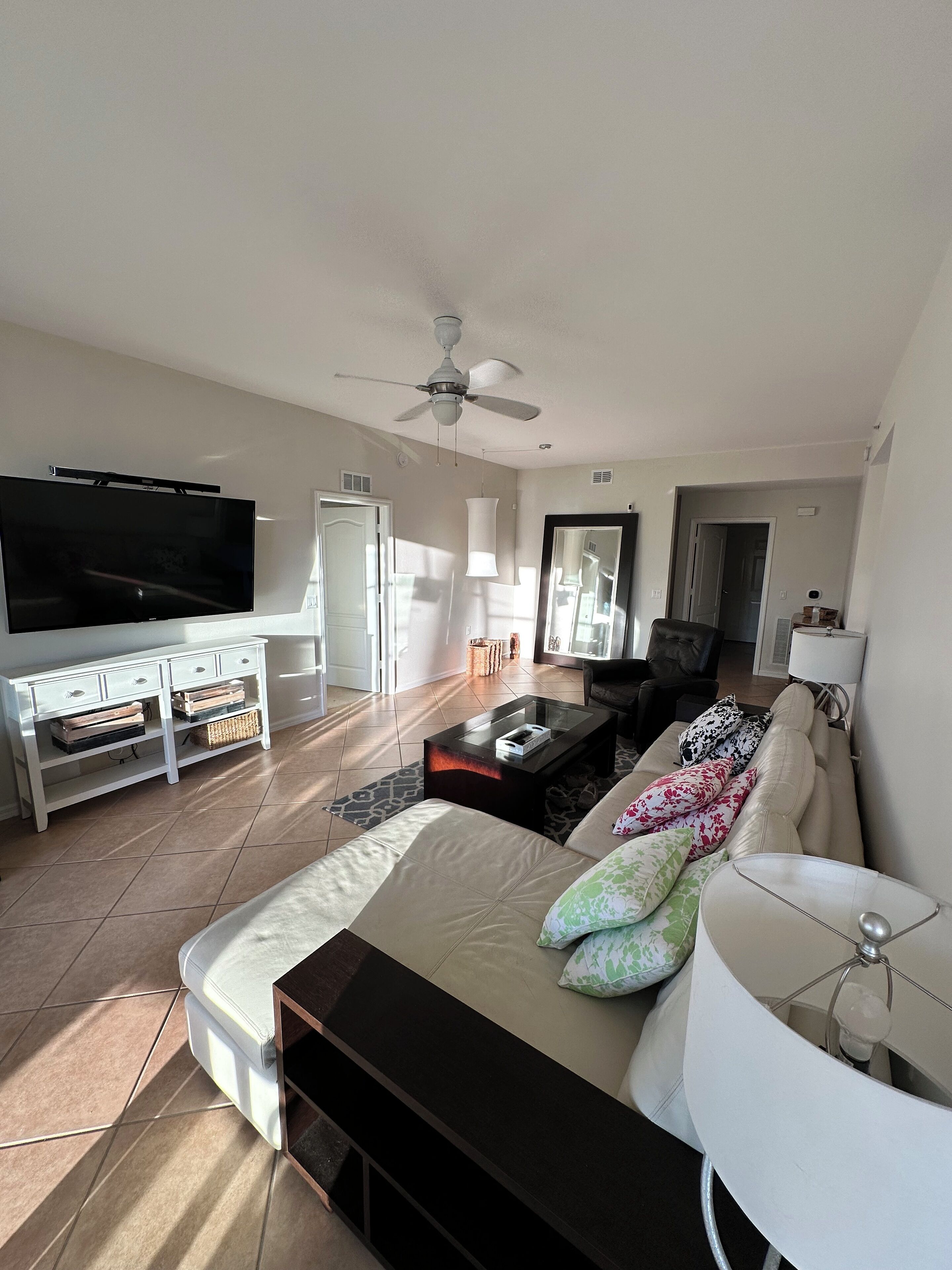 Ein modernes Wohnzimmer mit Flachbildfernseher, Deckenventilator, Sofa, Couchtisch und einem TV-Schrank mit Schubladen.