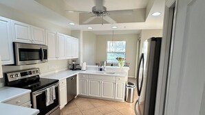 A modern kitchen with white cabinetry, stainless steel appliances, and a tiled floor.