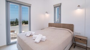 Une chambre dotée d’un grand lit, d’une tête de lit en bois, d’une table de chevet et donnant sur un espace extérieur grâce à une porte coulissante.