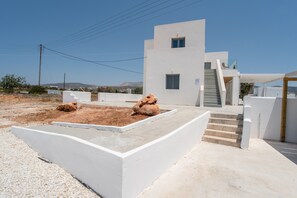 Un edificio moderno con techo plano, una escalera y un pequeño jardín rocoso.