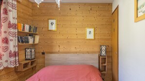 Une pièce aux murs lambrés, avec un lit, des étagères et des tableaux encadrés.