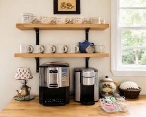 A kitchen with a coffee maker, a teapot, and a basket of coffee pods.
