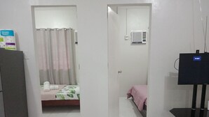 A hotel room with a bed, a television, and a bathroom visible through an open door. - Antonioville Subdivision (Mandaue)