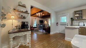 Una cocina amplia con pisos de madera, un comedor con una silla roja y una sala de estar con chimenea.