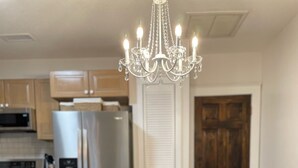 Una mesa de comedor con base blanca de pedestal, flanqueada por dos sillas tapizadas con diseño capitonado. En la mesa, hay un cuenco de madera.