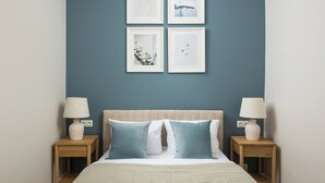 A bedroom with a bed, two nightstands, and four framed pictures on the wall. - Wola Ratusz Homely Apartment (Warszawa)