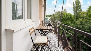 A balcony with a tiled floor, a wooden bench, and a chair with a cushion. - Wola Ratusz Homely Apartment (Warszawa)
