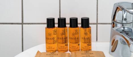 Four bottles of Havana body wash and two brown paper bags on a white surface.