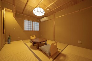 A tatami room with a shoji screen, tatami mat flooring, a low table, a cushion, and a hanging light fixture. - Saju Kyoto (Kyoto)