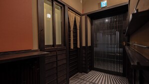 A hallway with wooden paneling, a tiled floor, and a sliding door with vertical bars. - Saju Kyoto (Kyoto)