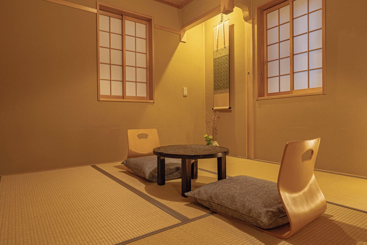 A traditional Japanese room with tatami flooring, a low table, and cushions.