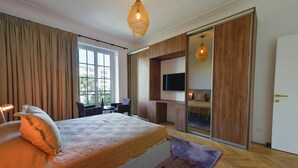 A bedroom with a large bed, a desk, a TV, and a sliding door closet.
