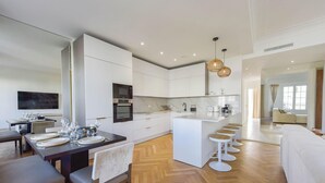 A modern kitchen with white cabinetry, a central island with bar stools, and a dining area with a table set for six.