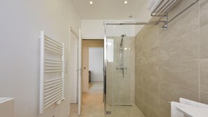 Une salle de bain moderne avec une douche à parois de verre, un porte-serviettes blanc et des toilettes apparentes.