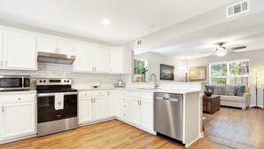 Una cocina moderna con armarios blancos, electrodomésticos de acero inoxidable y piso de madera.