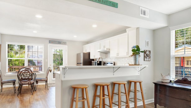 Una cocina moderna con armarios blancos, un refrigerador de acero inoxidable y una barra con taburetes.