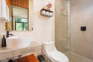A bathroom with a white sink, toilet, and glass shower enclosure. - Tuané Tulum (Tulum)