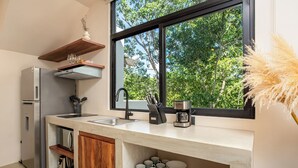 A modern kitchen with a large window, built-in appliances, and wooden shelves. - Tuané Tulum (Tulum)