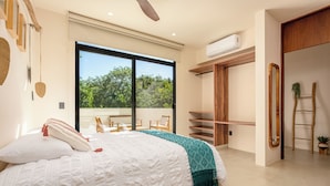 A modern bedroom with a large bed, a view of greenery outside, and a built-in wardrobe. - Tuané Tulum (Tulum)