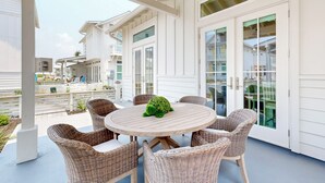 A covered patio with wicker furniture and a round table, featuring a green decorative centerpiece.
