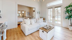 A spacious living room with a white sofa, a coffee table, and a large window.