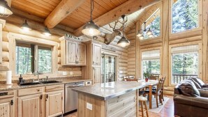 A log cabin interior with a kitchen, dining area, and a leather couch.
