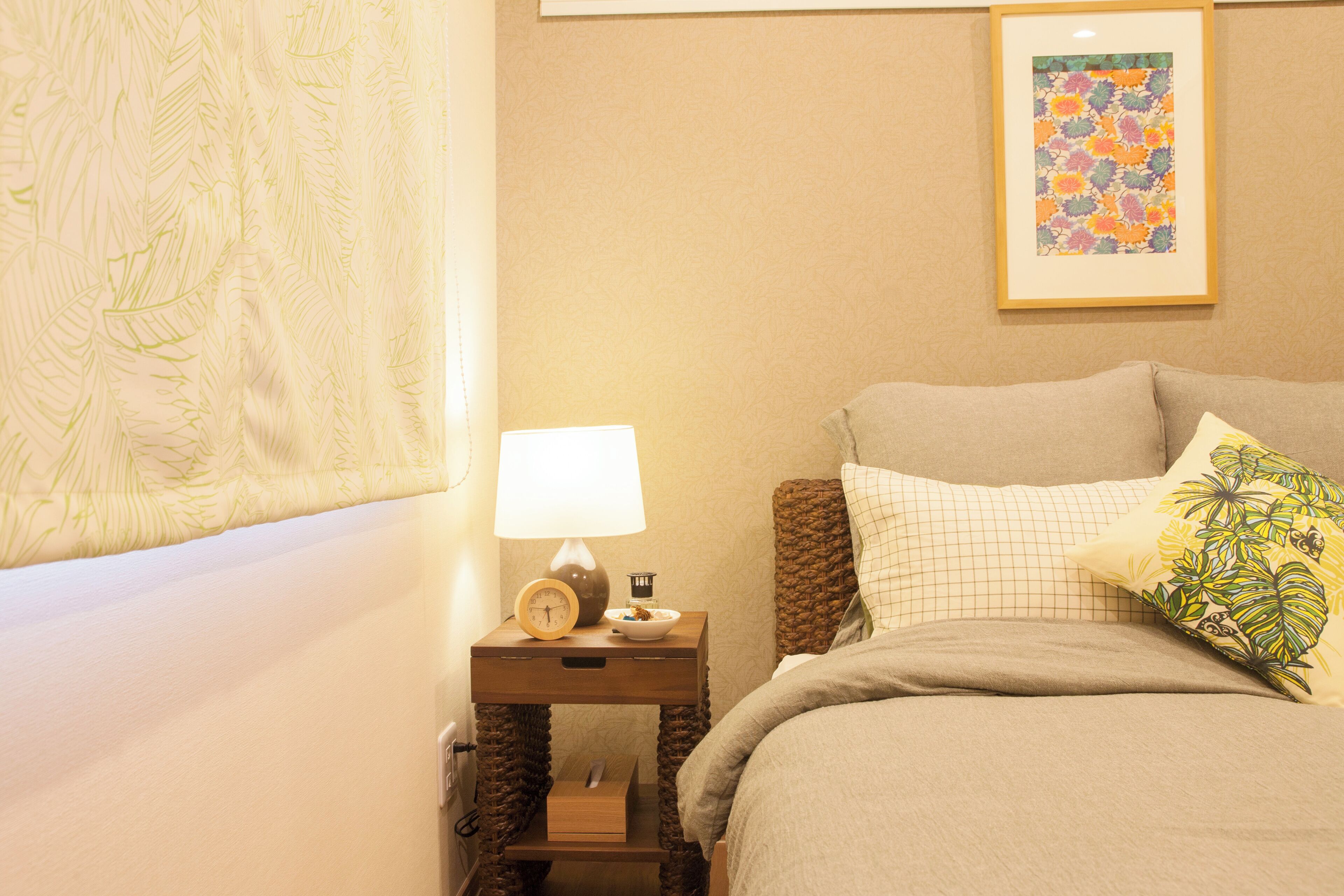 Un dormitorio ordenado con una cama, una mesita de noche con lámpara, un reloj y un cuadro en la pared.
