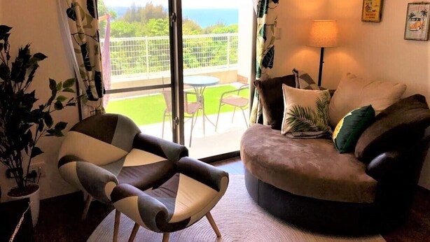 Un salón con sofá, sillón y vistas a un balcón con mesa y sillas.