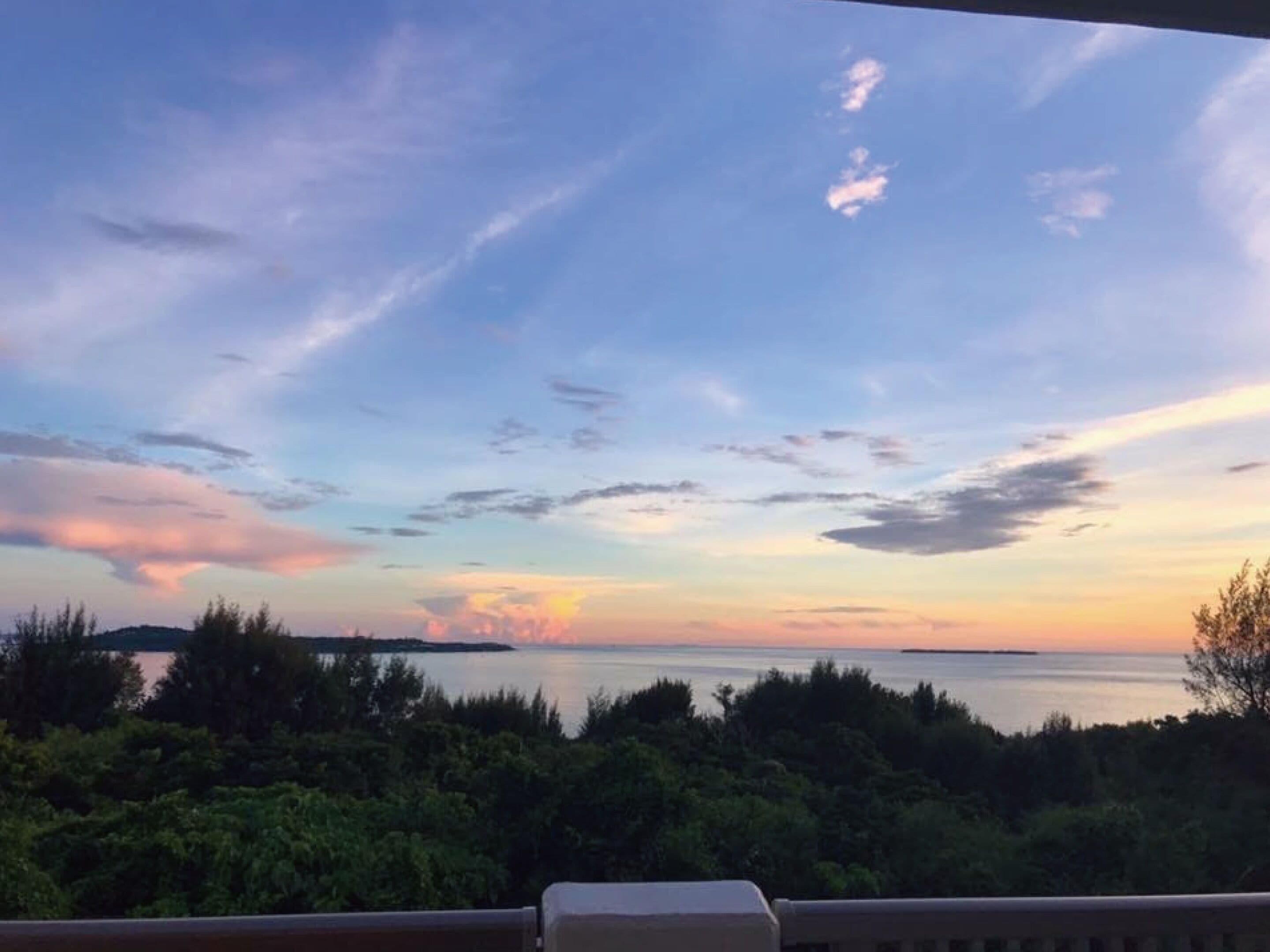 A view from a balcony overlooking a body of water with a sunset sky.