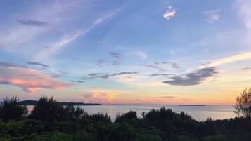 A view from a balcony overlooking a body of water with a sunset sky.