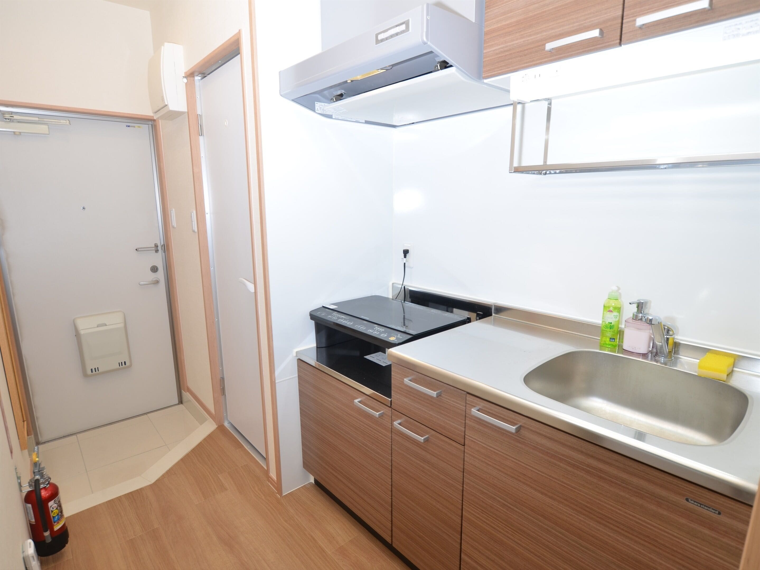 Une cuisine compacte dotée d’une cuisinière intégrée, d’un évier et d’armoires en bois.