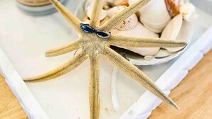 A tray with a starfish, a candle, and seashells. - Florida Beach Hideaway 2A– Near the Beach • Pool • Fast WiFi • free Parking (Fort Myers)