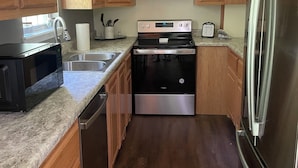 A kitchen with wooden cabinets, a stainless steel refrigerator, a black stove, and a dishwasher. - The Diamond Escape Murfreesboro Arkansas 3 miles to Crater of Diamond State Park (Murfreesboro)