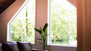 A room with a large window, a potted plant, and a brown leather sofa. - Updated Getaway in the hills of southern Indiana. Minutes from Starve Hollow SRA (Vallonia)