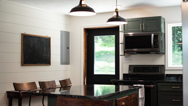 A modern kitchen with a central island, black cabinets, a microwave, and a stove. - Updated Getaway in the hills of southern Indiana. Minutes from Starve Hollow SRA (Vallonia)