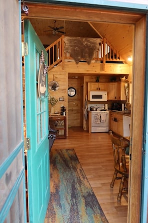A wooden interior with a kitchen, dining area, and a staircase leading to a loft.
