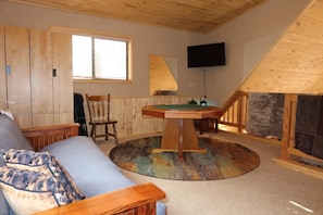 A cozy room with a sofa, a wooden table, a chair, a television, and a fireplace.