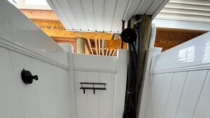 Un couloir étroit avec une porte blanche, une sonnette noire et un cadre de porte en bois.
