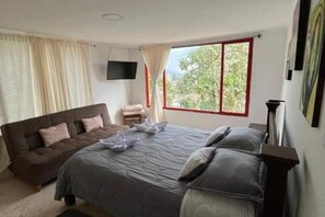 Relax in this inviting bedroom with a large bed, sofa, and flat-screen TV.
